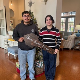 two people holding a wooden sign